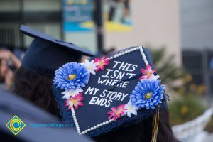 A graduation cap reads "This isn't where my story ends" at commencement