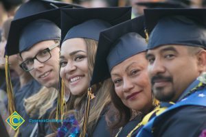 Students smile in graduation regalia at commencement