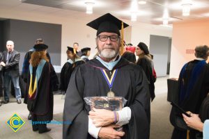 A faculty poses in graduation regalia at commencement