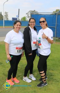 Women (AnnMarie Ruelas and Lili Perez) smiling at the camera, wearing athletic gear and race numbers