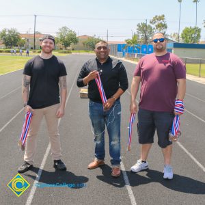 Three men holding medals on the track