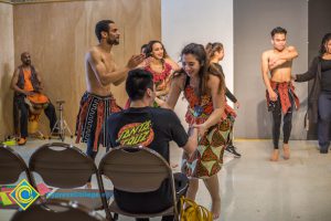 Dancers performing and getting a young man up from his seat.