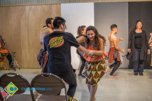 Dancers performing and getting a young man up from his seat.