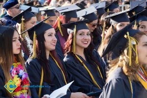 A student in graduation regalia smiles at the camera during commencement