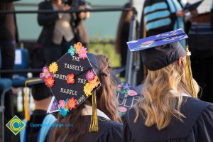 A graduation cap reads "The Tassel's Worth the Hassle" at commencement