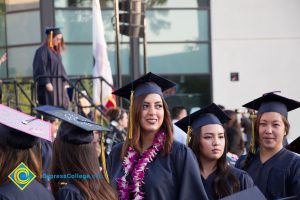 Graduates in regalia stand in the audience at commencement