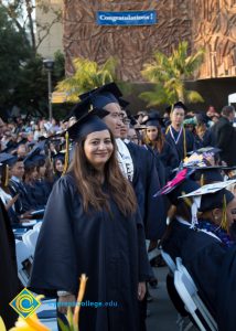 Graduates in regalia stand in the audience at commencement