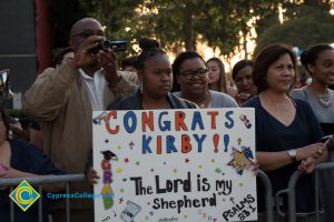 A family holds a sign supporting their graduate at commencement