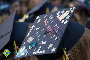 A graduation cap reads "This girl was meant to fly" at commencement