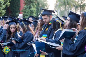 Graduates look at their diplomas during commencement