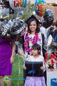A graduate poses with a young girl at commencement