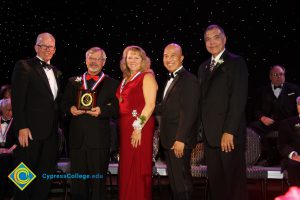 A woman in a red dress with President Bob Simpson and three other men in black suits.