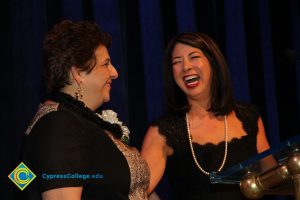 Two women with short brown hair and black shirts laugh during the 40th Annual Americana Awards.