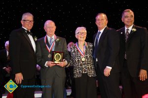 President Bob Simpson with a man in a grey suit and tie, holding an award, a woman in a black and white blouse and two men in suits at the 40th Annual Americana Awards.