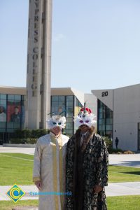 Two masked individuals standing with campanile in the background.