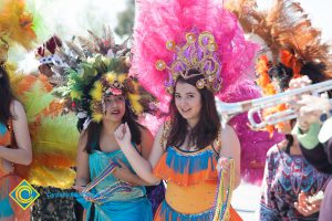 Two students wearing large headdresses for Mardi Gras parade.