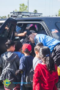 Children crowded to look inside a police car.