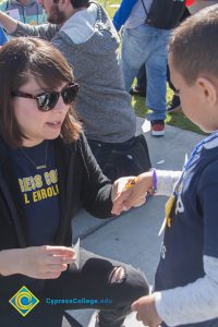 A woman putting a sticker on a little boys hand,