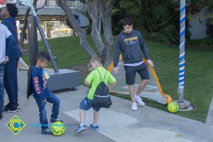 Two young boys and a young man playing with a soccer ball.