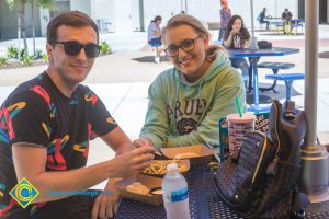 Two students eating lunch at round tables