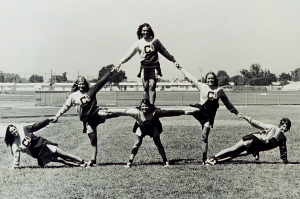 Cypress College cheerleaders form a pyramid on the campus track. Circa 1966.