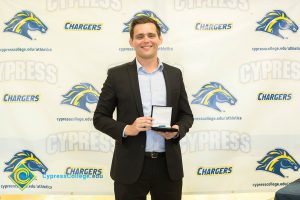 Man in a suit holding a medal.