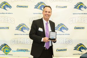 Man in a suit holding a medal.