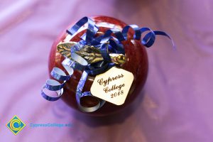 Ceramic apple with blue ribbon and gold tag that says Cypress College 2018