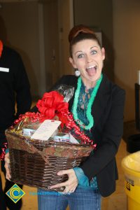 Raffle basket winner Summer Justice holding basket and wearing a green lei at end-of-the-year luau