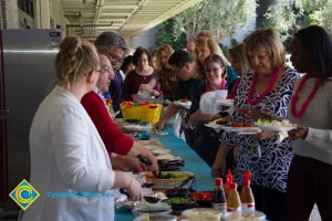 Employees wearing leis and getting food at end-of-the-year luau