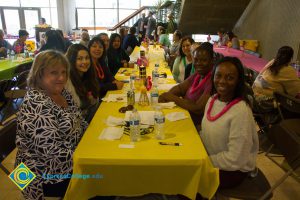 Employees sitting at table, wearing leis, at end-of-the-year luau