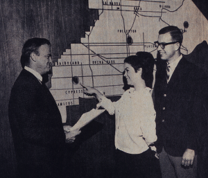 Two men and a young lady standing in front of the updated District map which includes Cypress College.