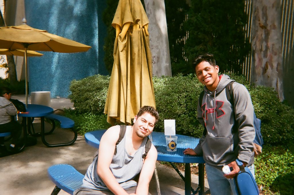 Two students pose for photo in front of tables. Photo taken for Disposable Camera Project.