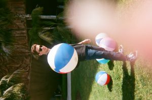 Student poses with beach balls in front of O'Cadiz concrete mural. Photo taken for Disposable Camera Project.