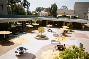 Tables with umbrellas in campus breezeway. Photo taken for Disposable Camera Project.