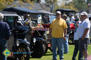 Men looking at antique cars parked on the campus lawn.