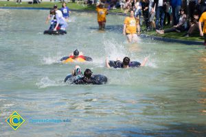 People in the pond swimming in inner tubes.