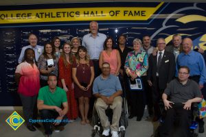 A group of men and women standing in front of the Cypress College Athletics Hall of Fame.