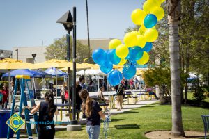 Set up for the 50th Anniversary Festival and Reunion with a young lady holding a bunch of yellow and blue balloons.