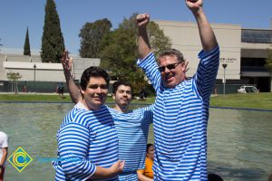 Three men with arms raised in old time bathing suits.