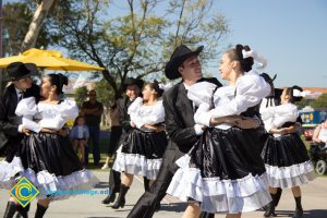 Women in black and white dresses and men in black suits and hats dancing at the 50th Anniversary Festival and Reunion.