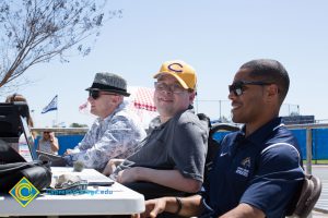 Wesley McCurtis and two other men sit at an outdoor table at a sporting event.