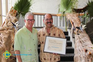 President Bob Simpson and Albert Miranda holding an award.