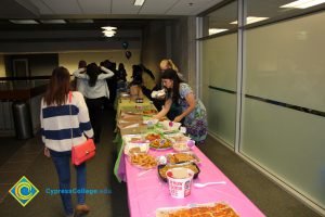 Potluck table with people waiting to be served.