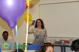 Woman holding up pamphlets at the 2014 ESL potluck.