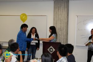 A young man in a blue jacket receiving an award at the 2014 ESL Scholarship Potluck.