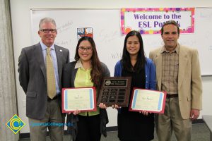 Two young ladies holding awards with President Bob Simpson and Eldon Young.