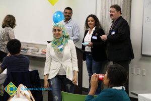Phil Dykstra, Santanu Bandyopadhyay and another staff member watch as a young lady in a white jacket and colorful hijab walks away.