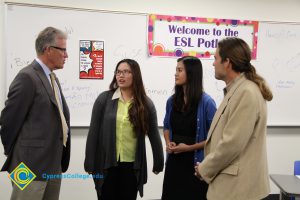Eldon Young and President Bob Simpson speaking with two young women at the ESL welcome potluck.