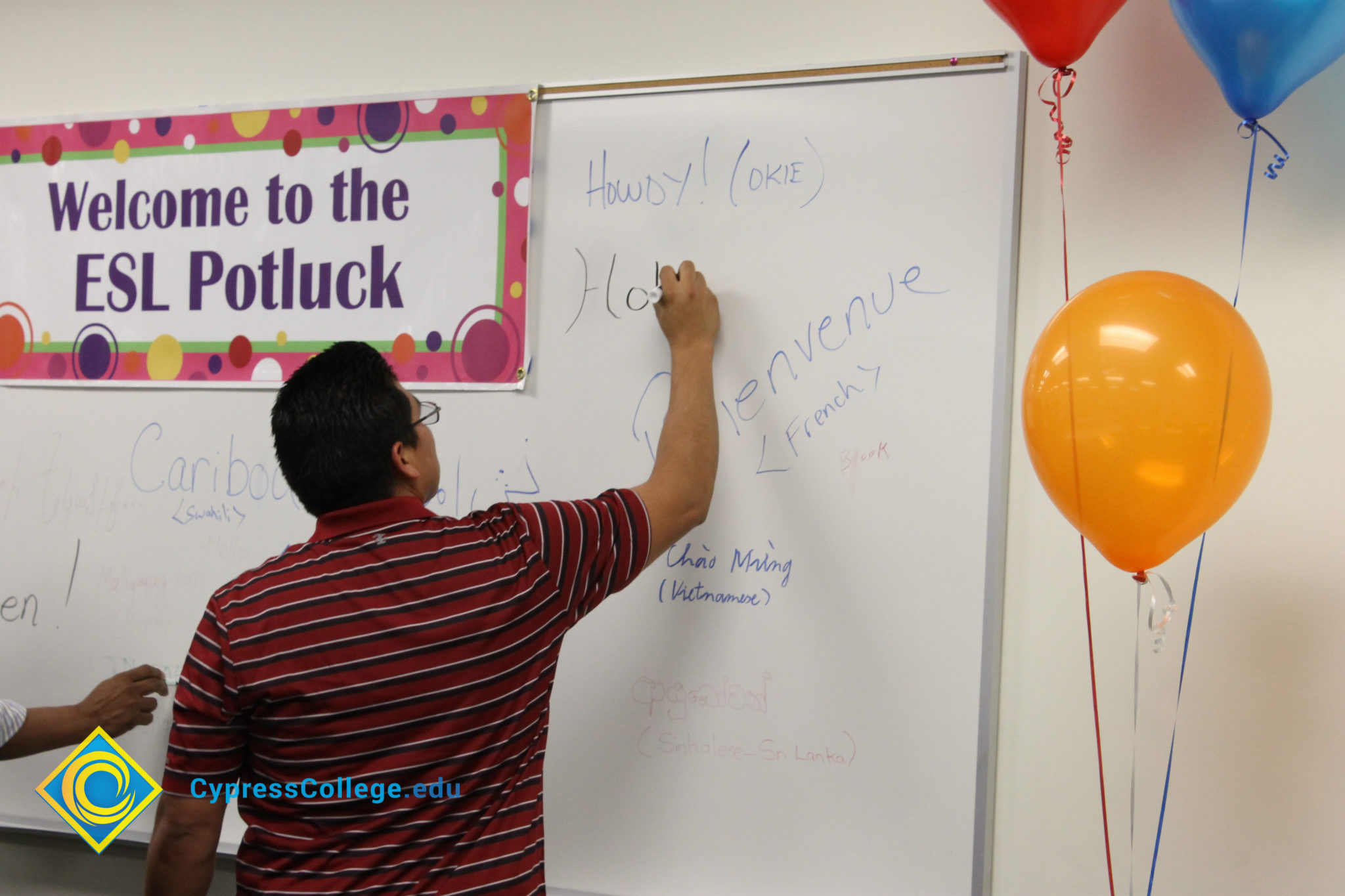 A man in a red and white striped shirt writing on a white board.